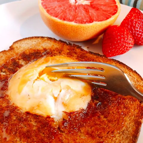 cutting into eggs in toast with a fork