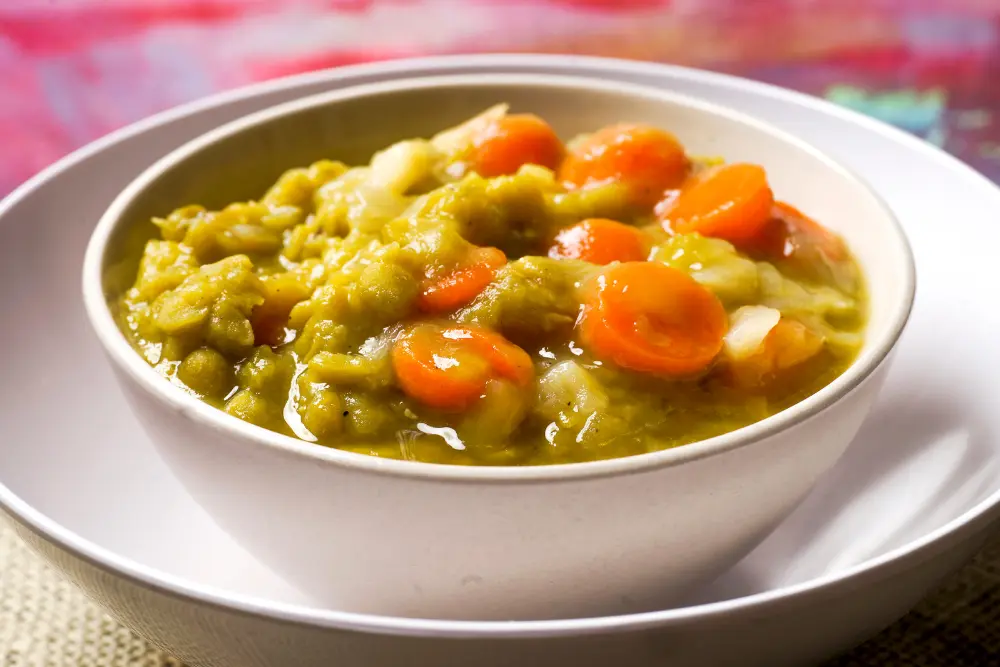 split pea soup with carrots in white bowls