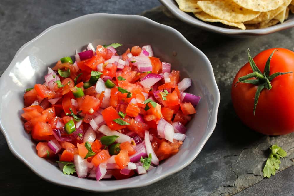 fresh tomato salsa in bowl next to tomato