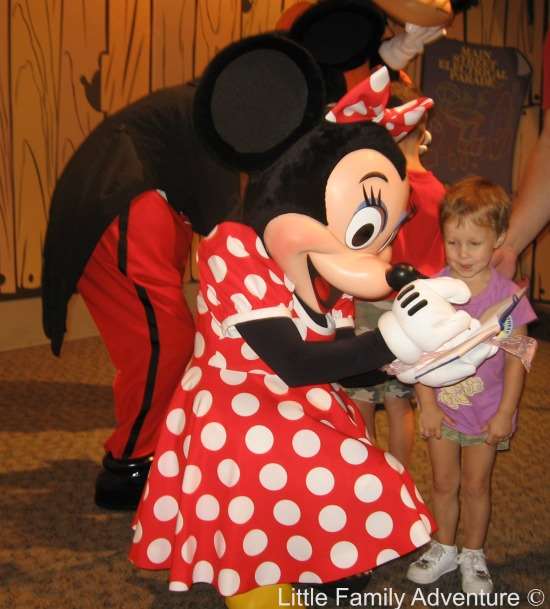 little girl standing by Minnie Mouse