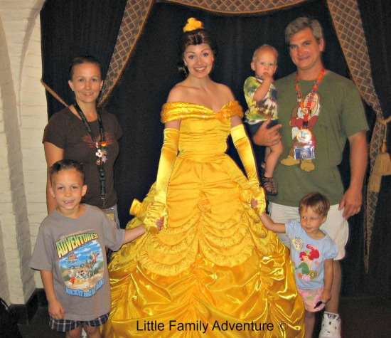 Family with toddlers taking picture with princess in yellow dress