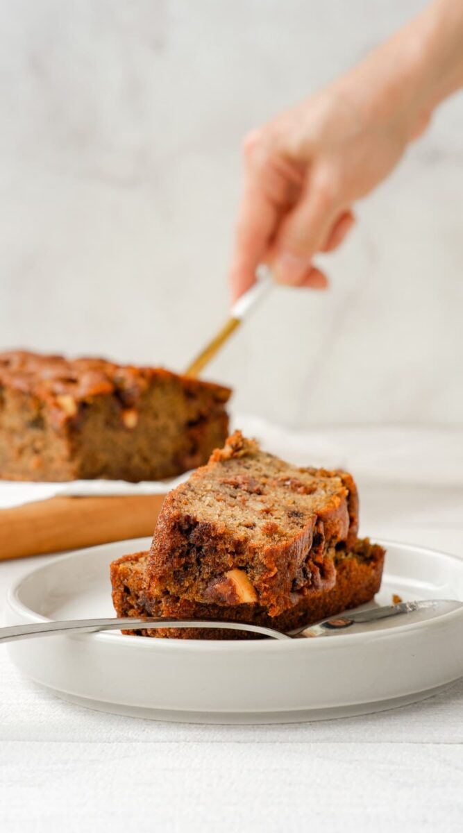 banana bread slices on plate, hand cutting bread