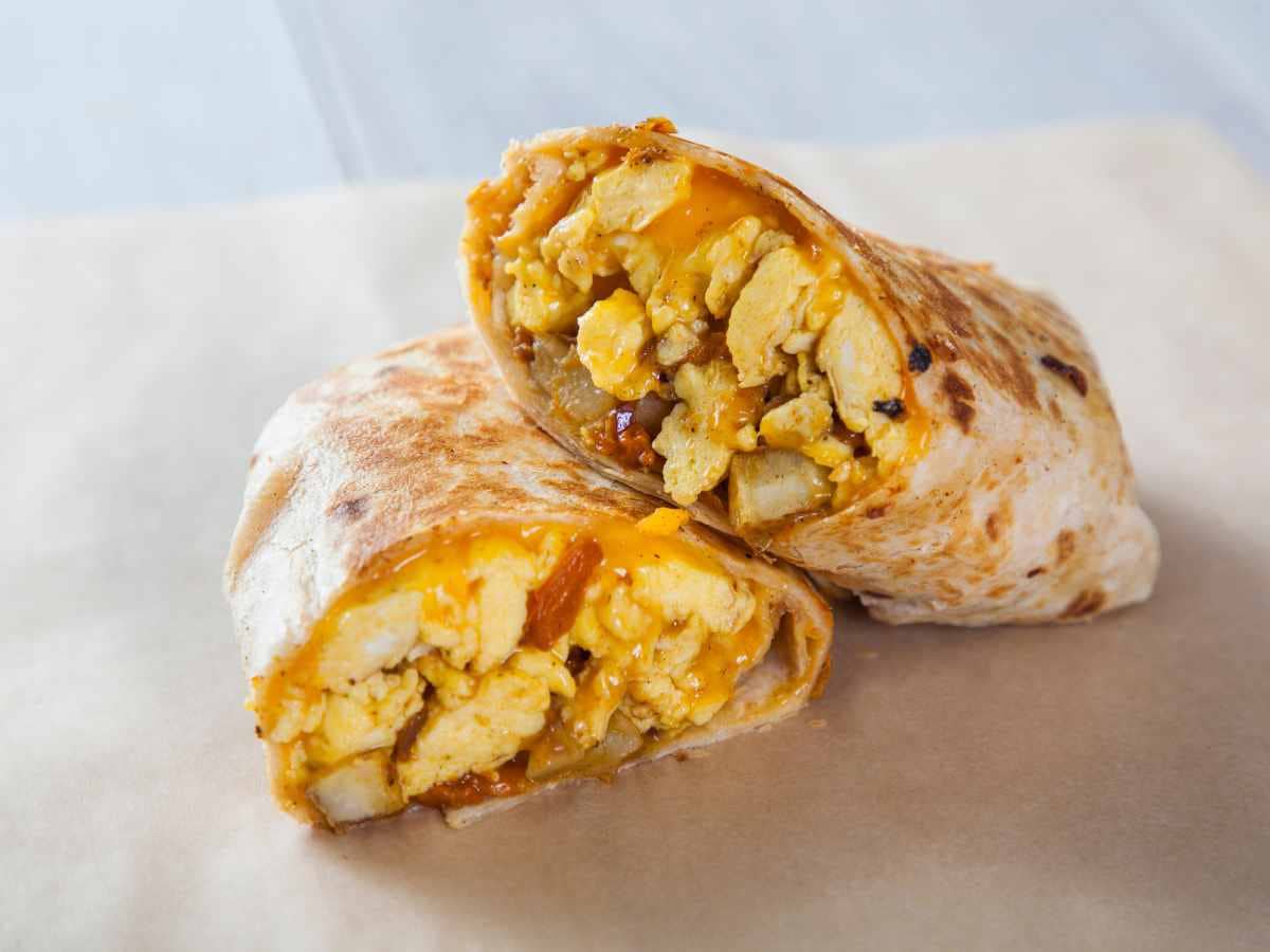 eggs and sausage inside camping breakfast burritos on parchment paper