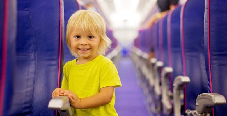toddler in yellow shirt standing in aisle of airplane