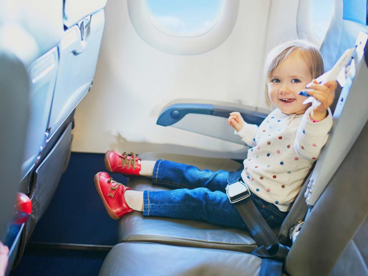 toddler girl holding toy airplane in an airplane seat with activities for toddlers