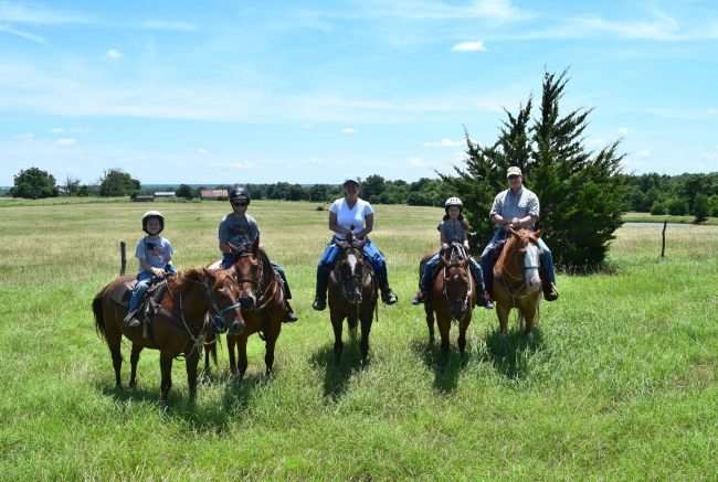 family o n horseback on a grassy field