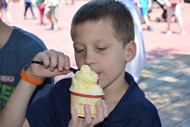 boy eating pineapple soft serve in a cup (Dole Whip)