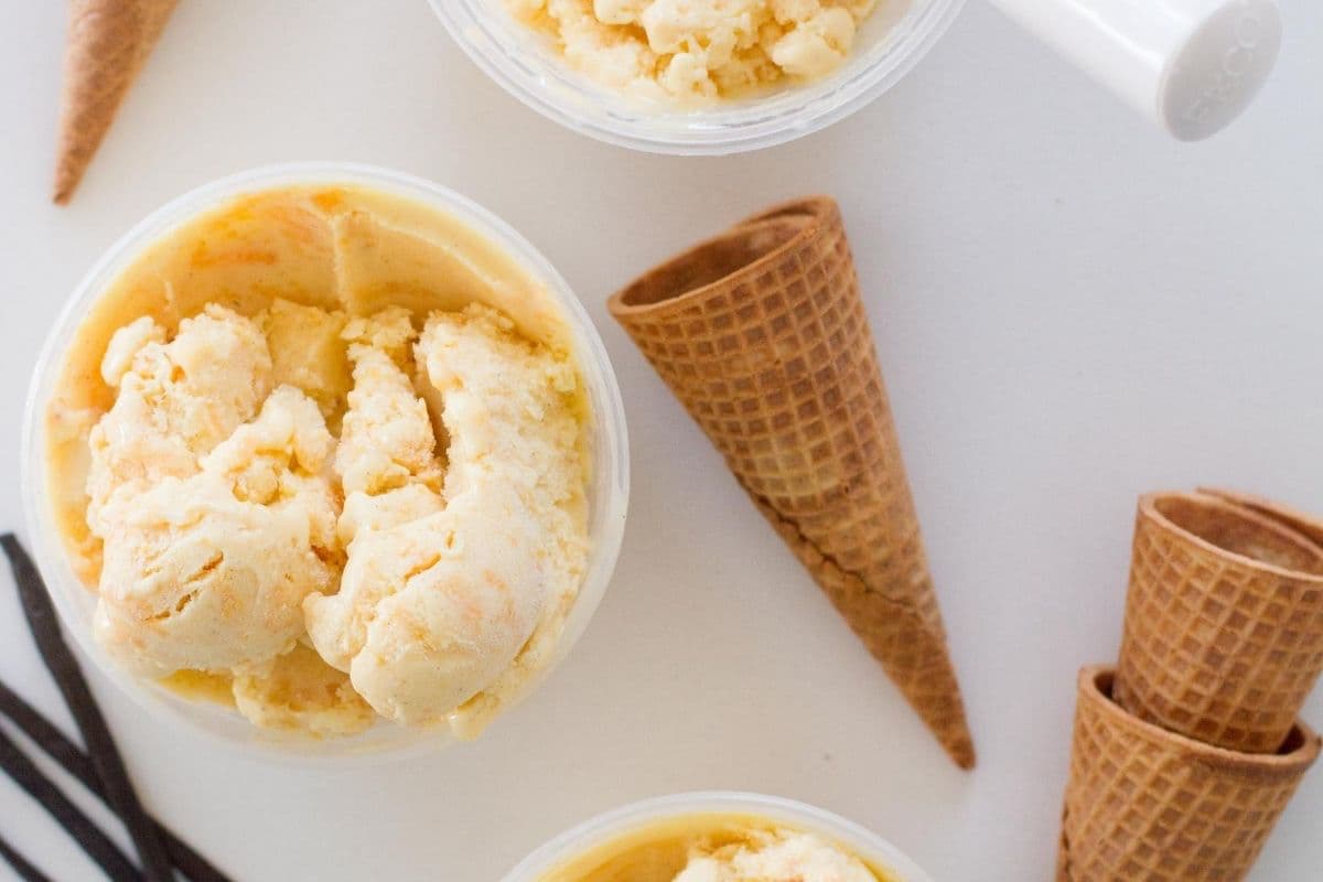 peach ice cream in cup aside sugar cones