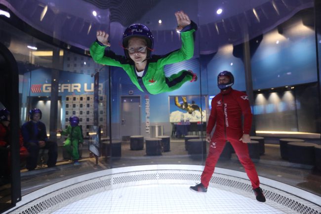 Girl and instructor inside a wind tunnel at iFly