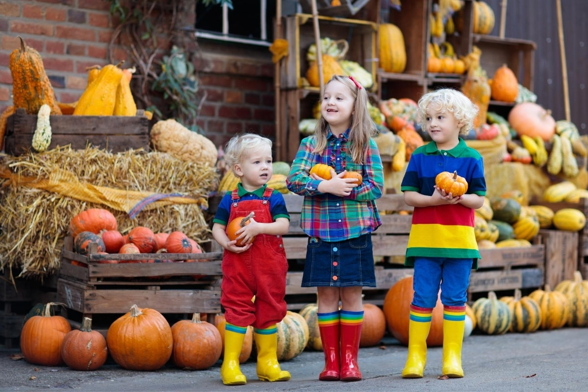 children with pumpkins at a farm stand