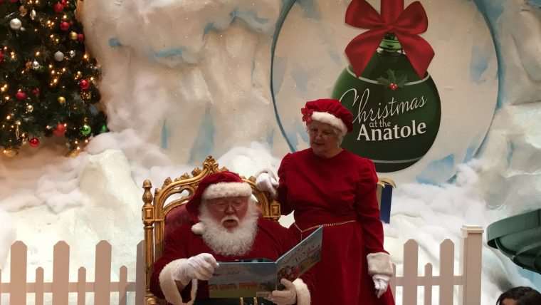 Santa reading a story with Mrs. Claus looking over shoulder