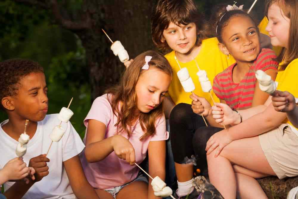 Kids roasting marshmallows on sticks by the campfire