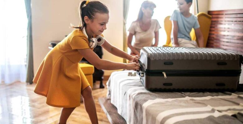 Girl closing suitcase and getting settled in htoel room with mom and brother