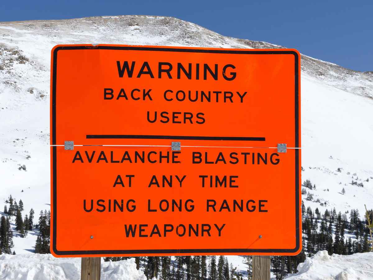 bright orange sign warning back country users in the Rocky Mountains of avalanche blasting