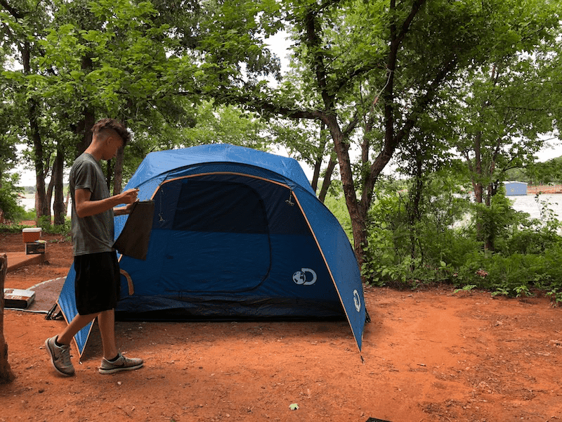 camping tent with teen in front - Ensure Your Next Family Camping Trip is Epic with these Summer Planning Tips