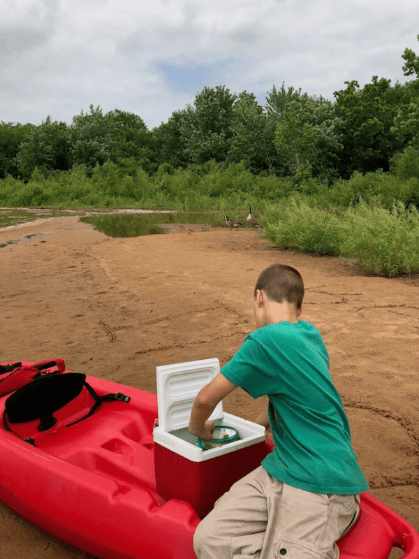 boy grabbing snack from ice cooler - Ensure Your Next Family Camping Trip is Epic with these Summer Planning Tips