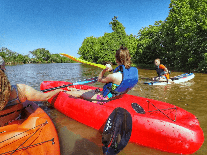 family kayaking on calm lake with kids