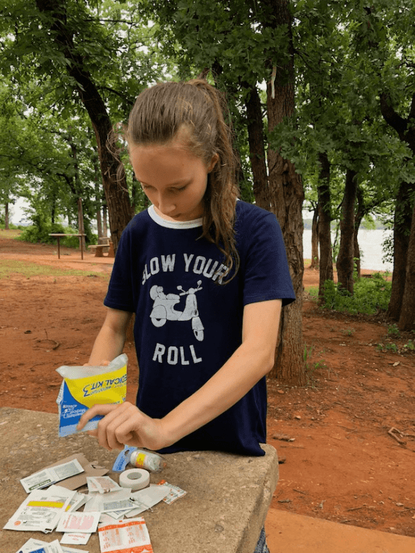 Girl going through a first aid kit - Ensure Your Next Family Camping Trip is Epic with these Summer Planning Tips