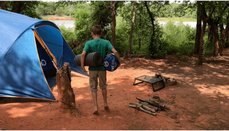 boy holding sleeping bags at camp site