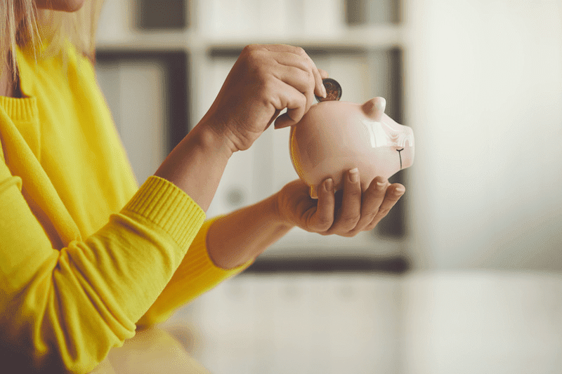 woman putting moey in piggy bank