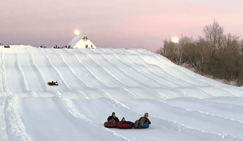snow tubing on hill at sunset