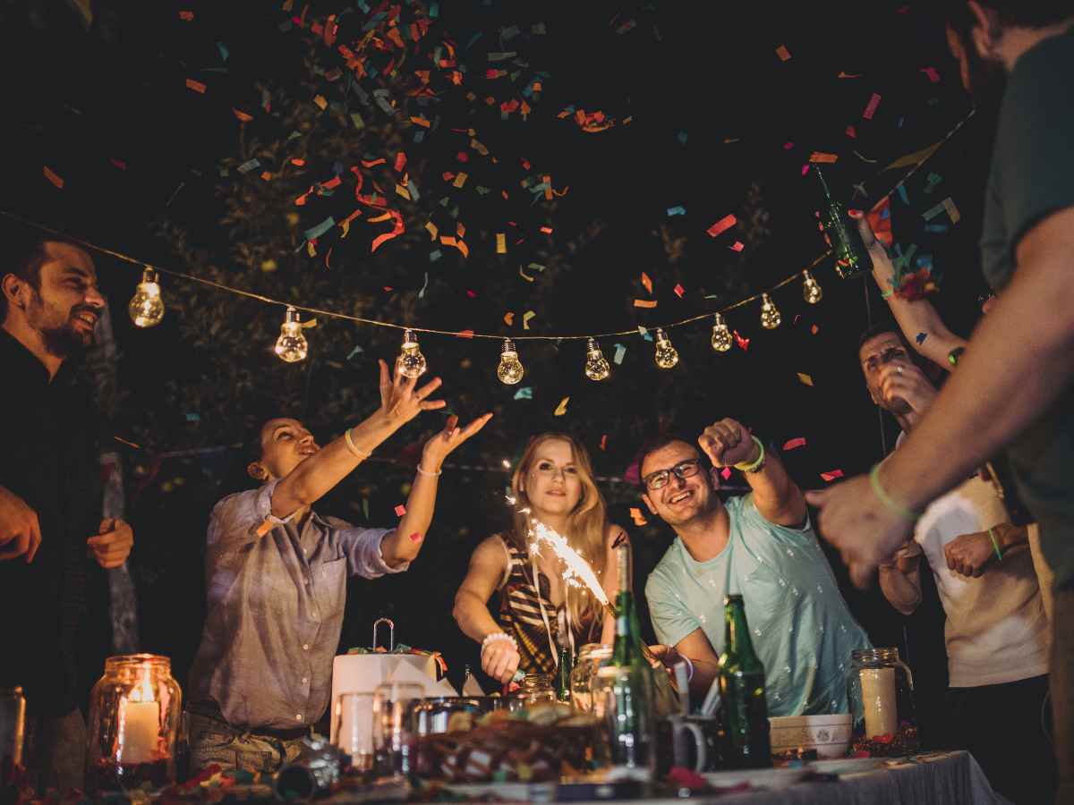 friends and family hanging string lights for backyard bbq party