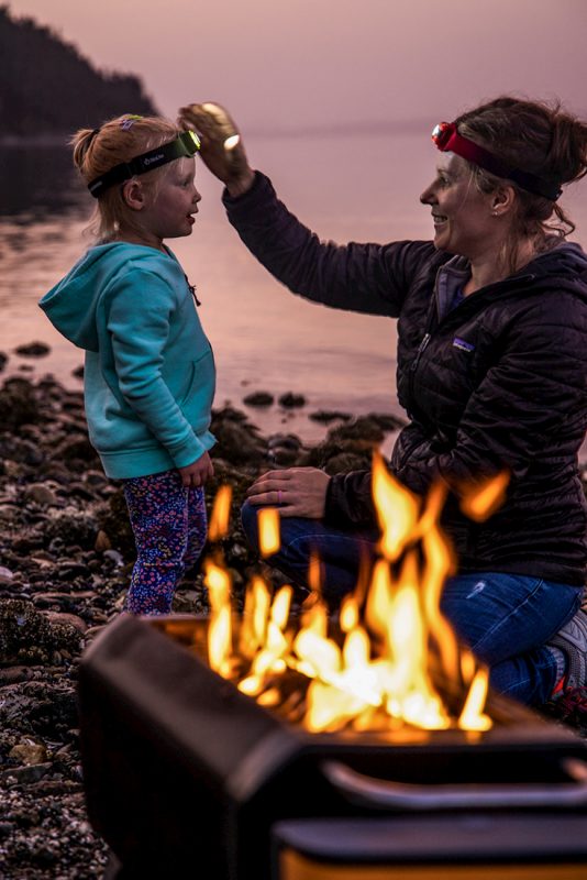 woman and child lakeside in front of fire