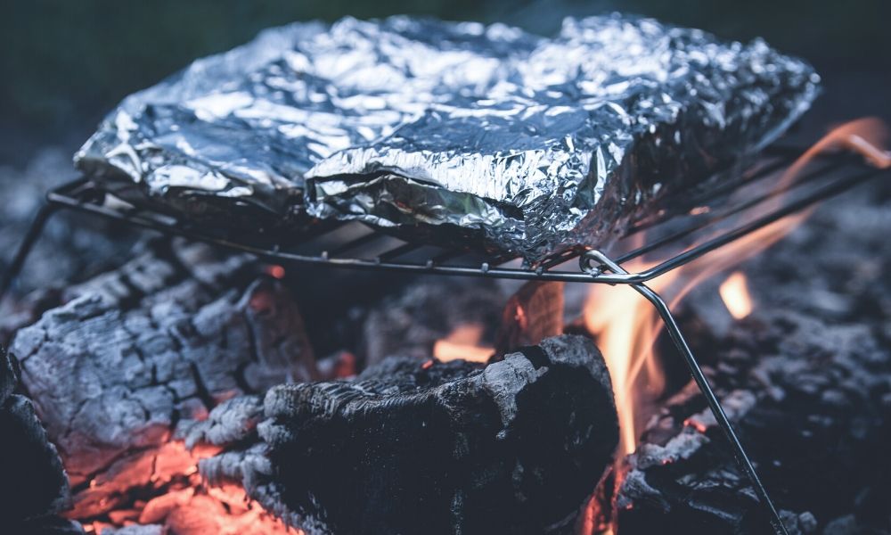 foil packets cooked on grate over campfire