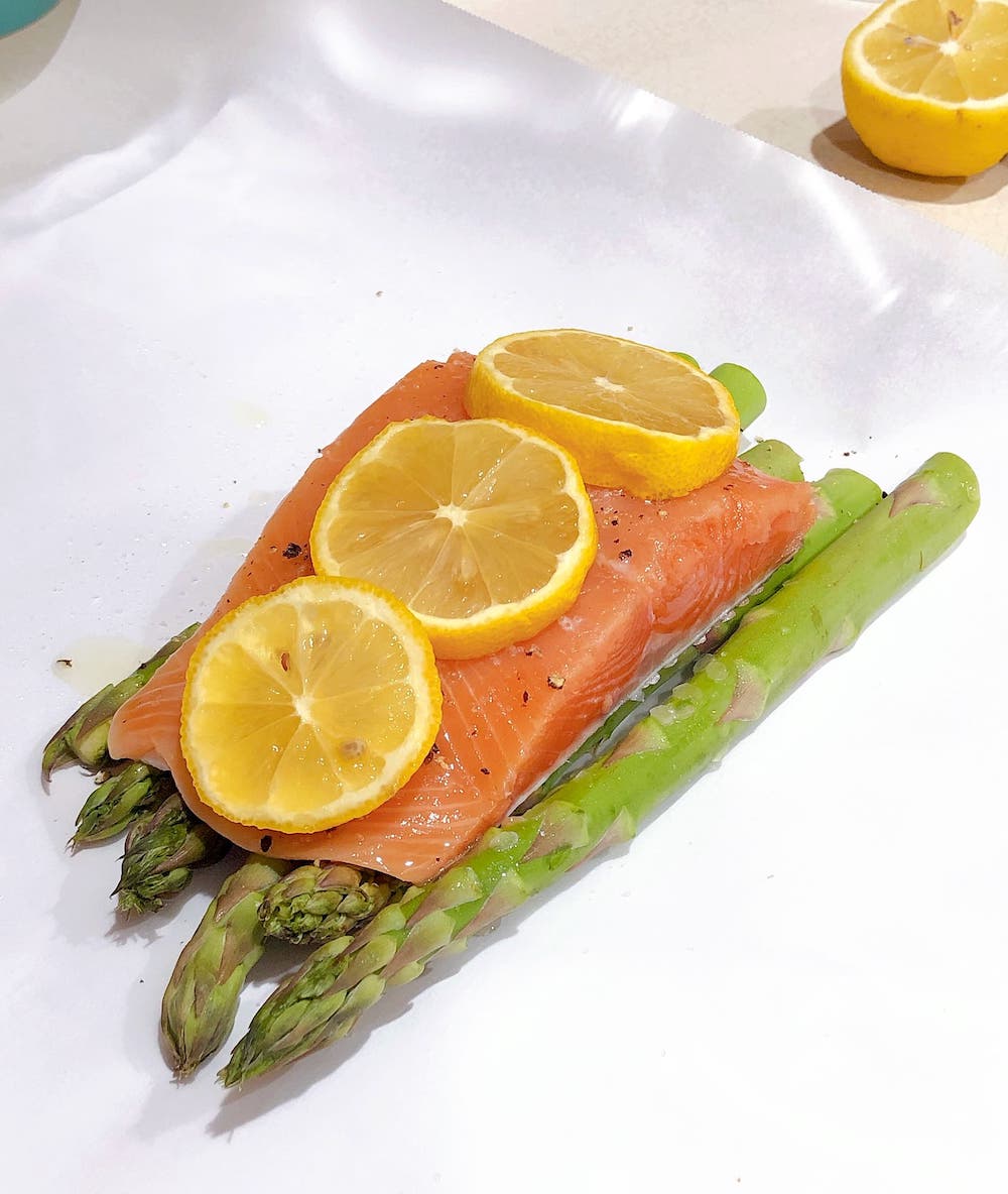 Salmon and asparagus with lemon slices on parchment paper