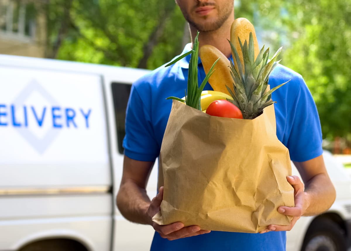 man delivering brown sack of groceries