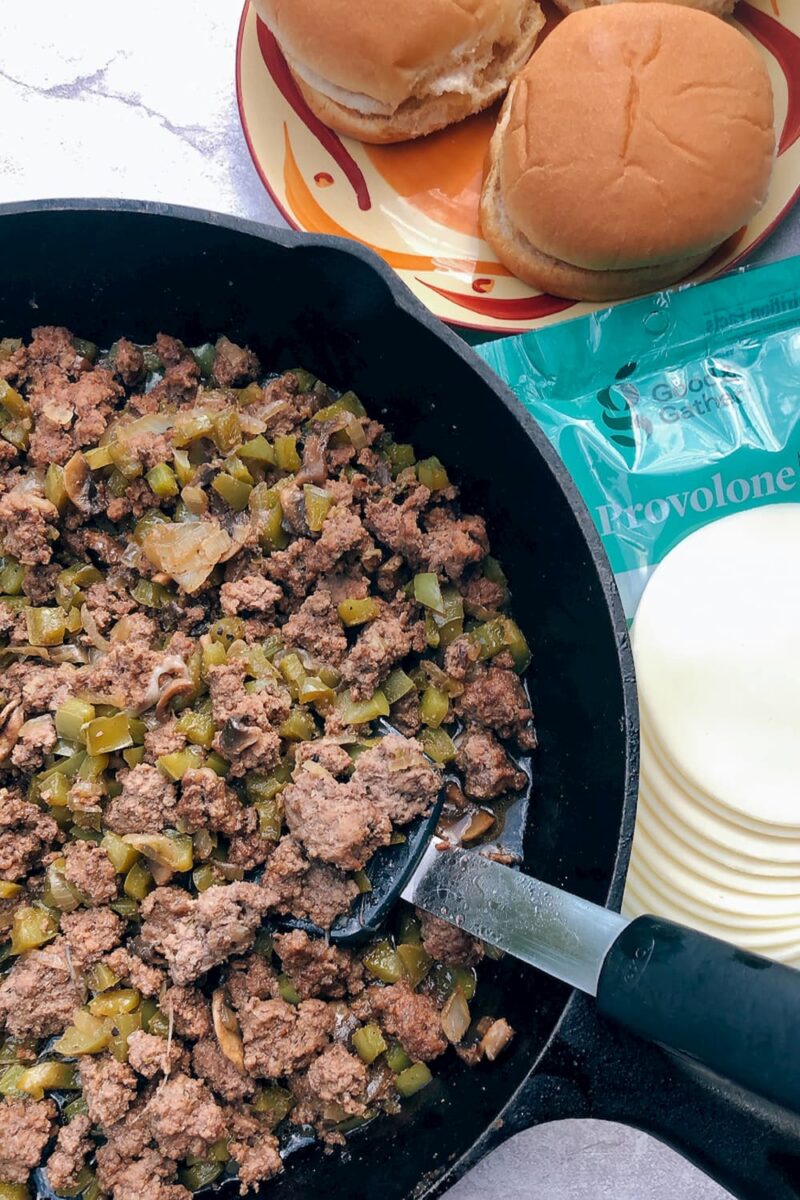 grund beef, onions, and peppers alongside sliced cheese and buns for sloppy joes cheesesteak