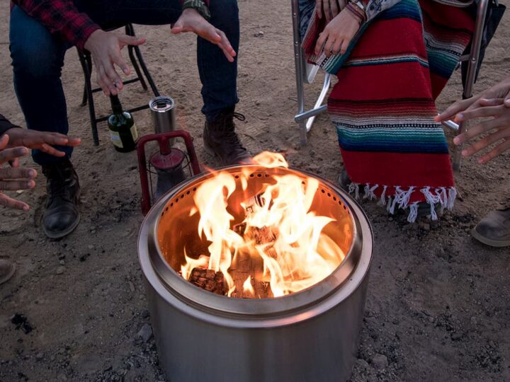 metal campfire fire with fire - campers warming up behind it