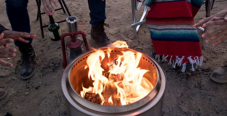 metal campfire fire with fire - campers warming up behind it