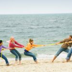 teens playing tug o war on beach