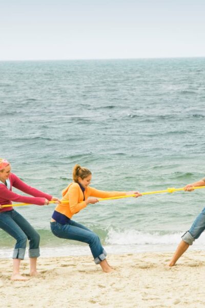 teens playing tug o war on beach