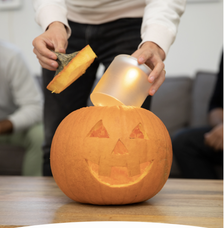 woman putting candle in carved pumpkin