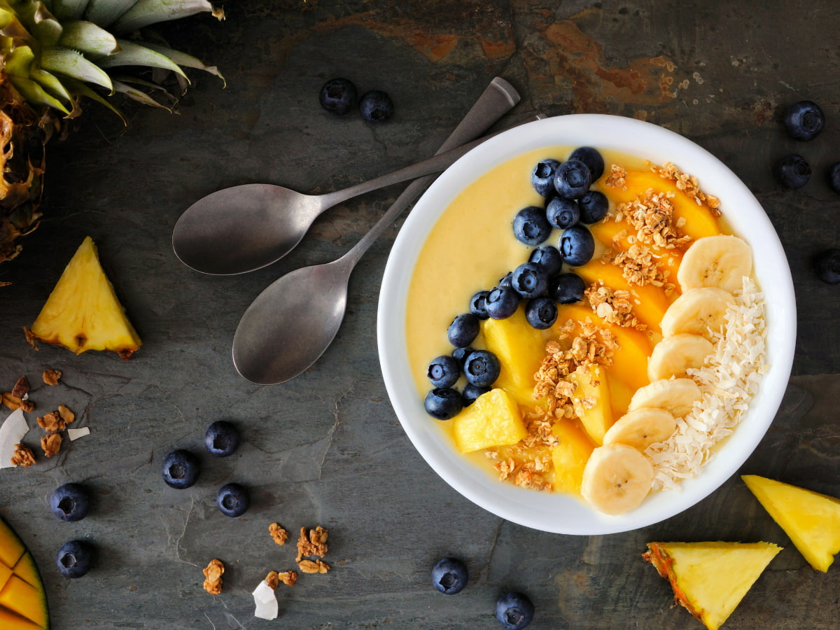 fruit smoothie bowl with fruit around it