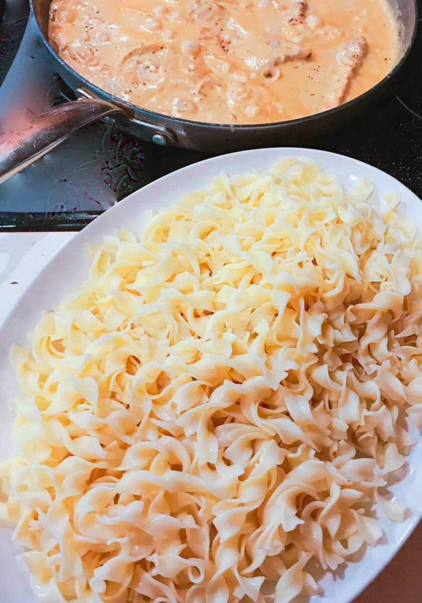broad egg noodles on platter and gravy in pan