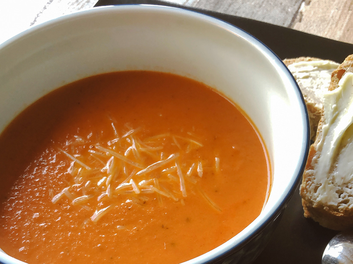 tomato soup in a bowl alongside butter bread