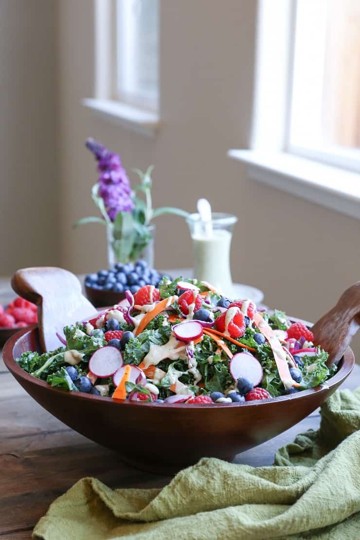 kale, blueberry, radish salad with dressing in a wooden bowl