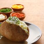 Baked potato bar with bacon, cheese, sour cream, and chive toppings