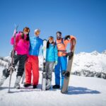 family dressed to go skiing holding their skiis, mountains and skiing, family travel