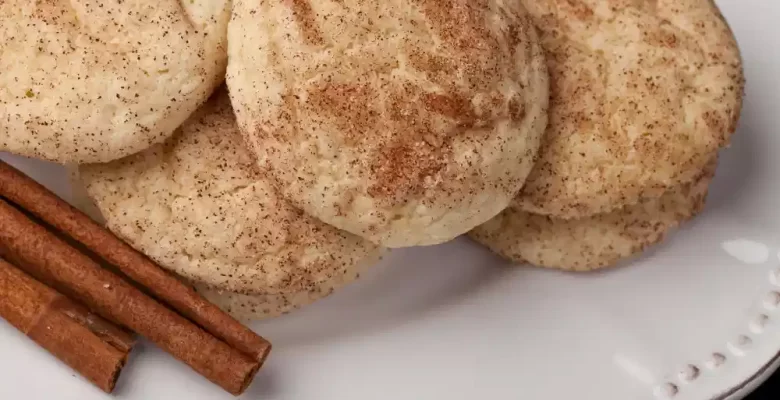chewy snickerdoodle cookies on white plate with cinnamon stick on side