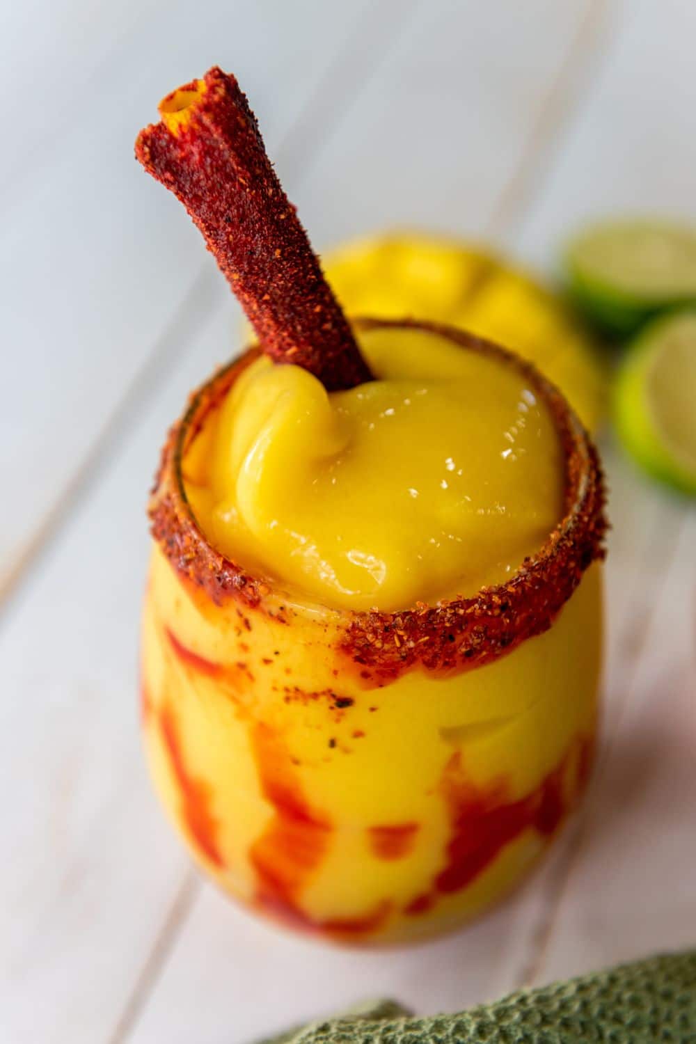 Glass of Mexican Mangonada rimmed with tajin and a tamarind candy straw