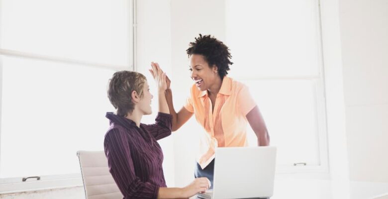 two women high fiving behind laptop