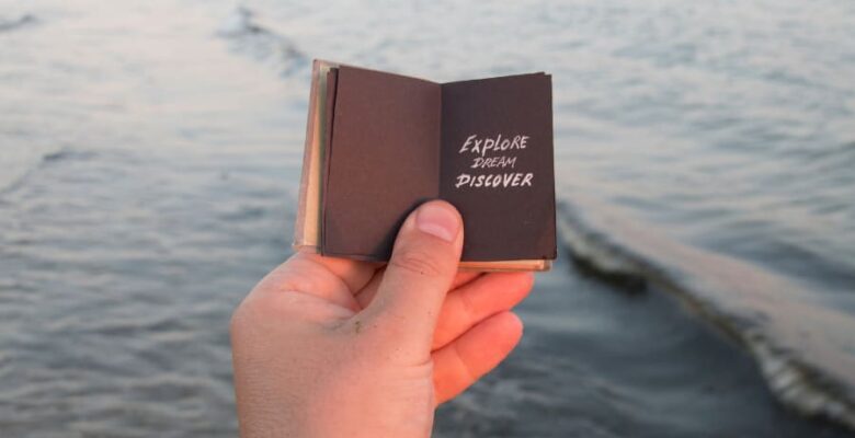 Discover dream explore travel quote writing in mini book held by a hand