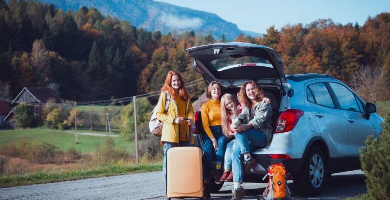 family sitting in back of car for road trip in fall