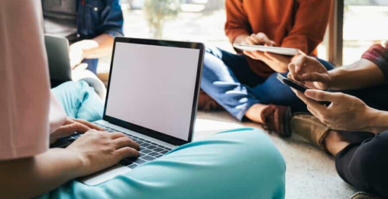 teens on laptops seating in a circle