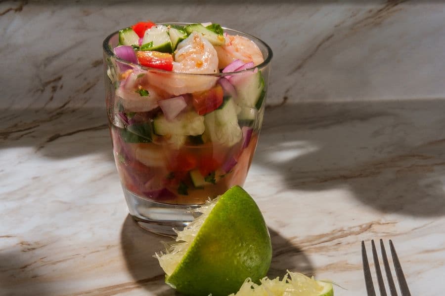 glass of shrimp ceviche with juiced lime in the foreground