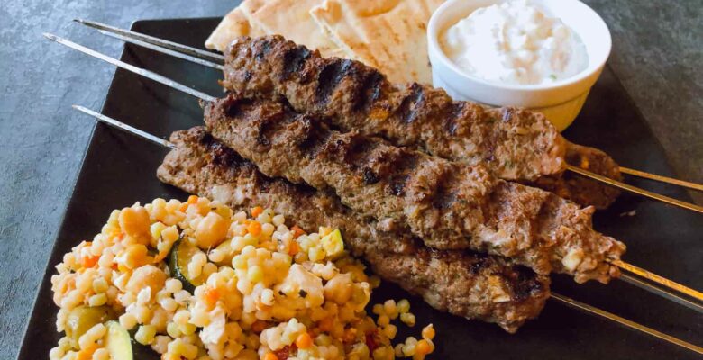 Moroccan beef kebabs on skewers with a salad and yogurt sauce